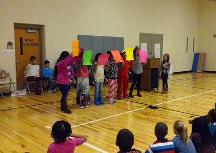 During a student's speech, she has friends hold up colorful signs.