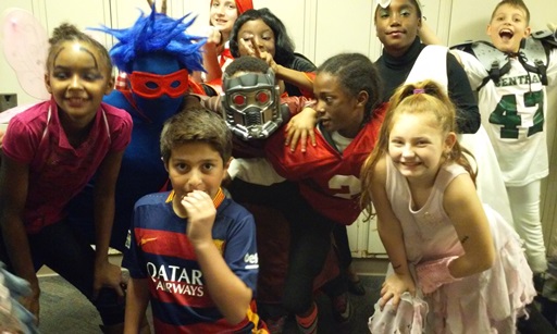 A group of kids smile as they pose in costume. A fairy, soccer and football stars, cheerleader, star lord, and a few others.