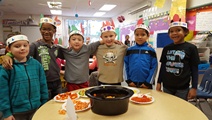 Kids in Mrs. Dykstra's class wrap their arms around each other as they look at their meal.