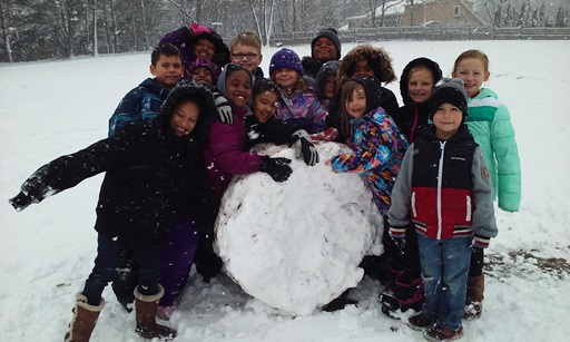 Students happily gather around a large snowball.
