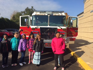 Six students pose happily in front of the fire truck.